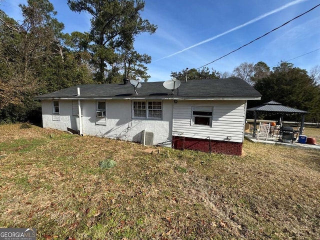 back of property featuring central AC unit, a gazebo, and a lawn