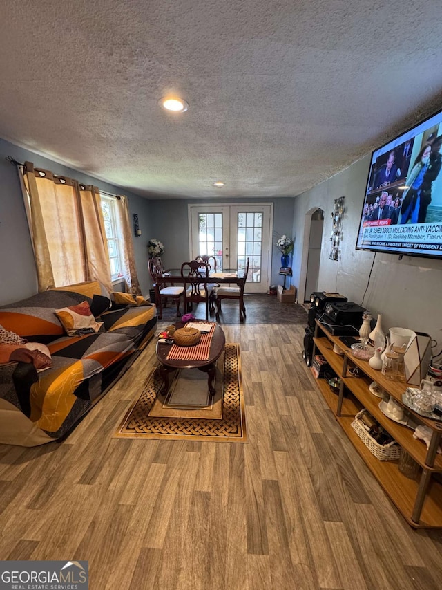 living room with wood-type flooring, a textured ceiling, and french doors