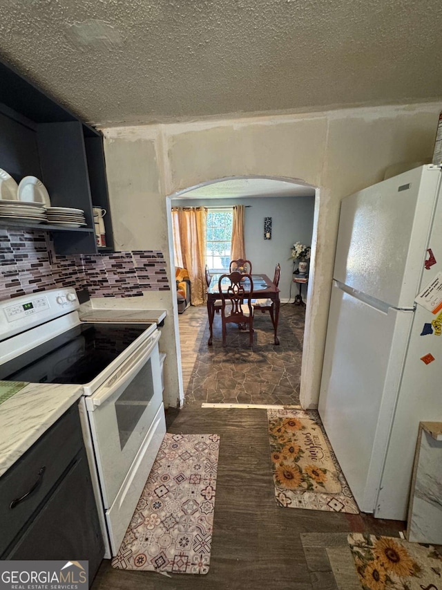 kitchen featuring a textured ceiling, white appliances, and decorative backsplash