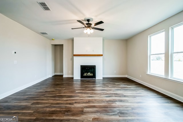 unfurnished living room featuring ceiling fan, dark wood-type flooring, and a fireplace