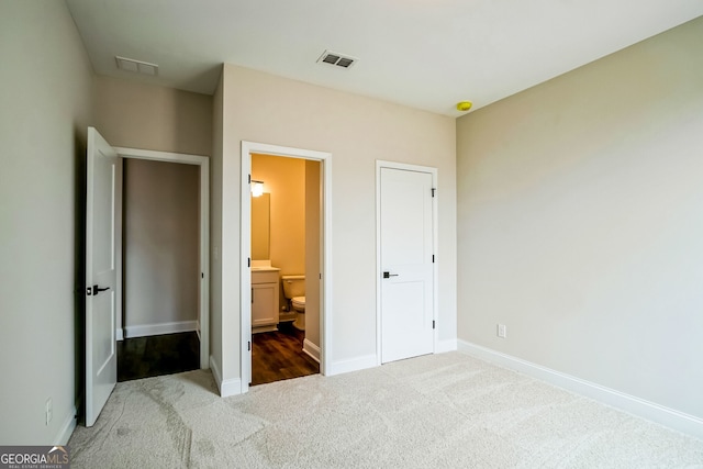 unfurnished bedroom featuring ensuite bath and carpet floors