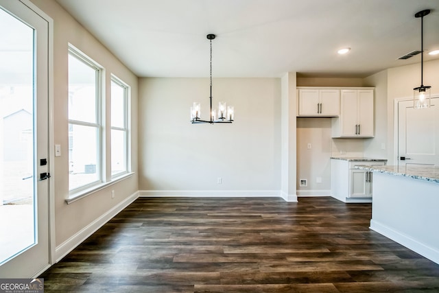 unfurnished dining area with an inviting chandelier and dark hardwood / wood-style flooring