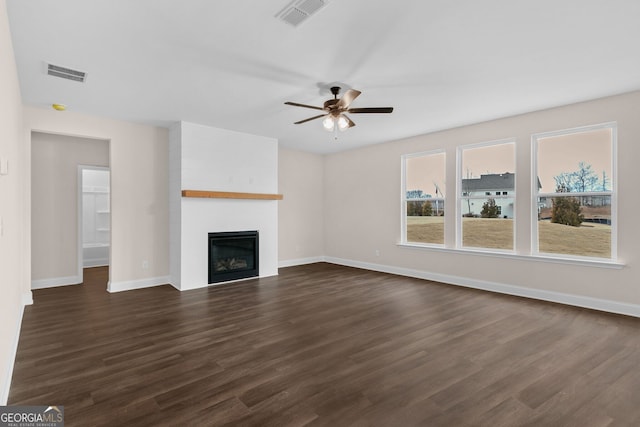 unfurnished living room featuring ceiling fan, a large fireplace, and dark hardwood / wood-style floors