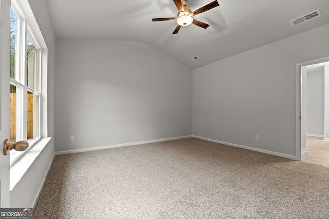 carpeted spare room featuring vaulted ceiling and ceiling fan