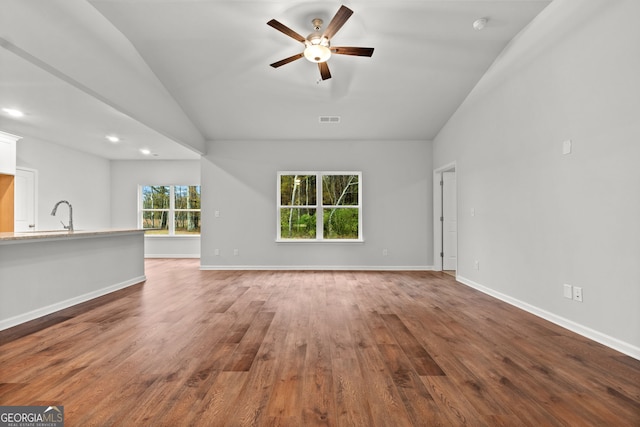 unfurnished living room with vaulted ceiling, dark hardwood / wood-style floors, sink, and ceiling fan