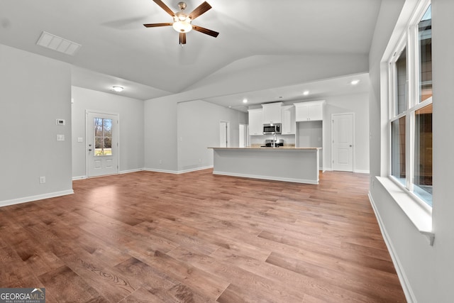 unfurnished living room featuring vaulted ceiling, light hardwood / wood-style floors, and ceiling fan