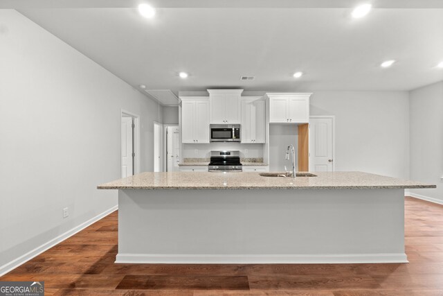 kitchen with white cabinetry, appliances with stainless steel finishes, sink, and a kitchen island with sink