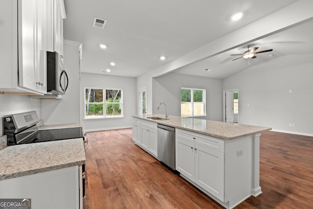 kitchen with appliances with stainless steel finishes, sink, white cabinets, light stone counters, and a center island with sink