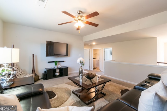 living room with washer / dryer, light carpet, and ceiling fan