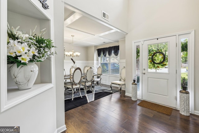 entrance foyer with dark hardwood / wood-style flooring, coffered ceiling, and an inviting chandelier