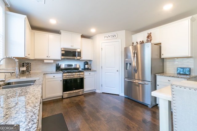 kitchen featuring dark hardwood / wood-style floors, tasteful backsplash, sink, white cabinets, and stainless steel appliances