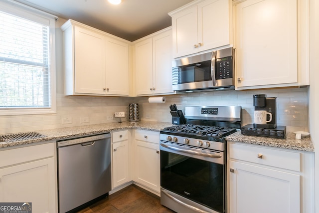 kitchen featuring stainless steel appliances, white cabinets, and light stone counters