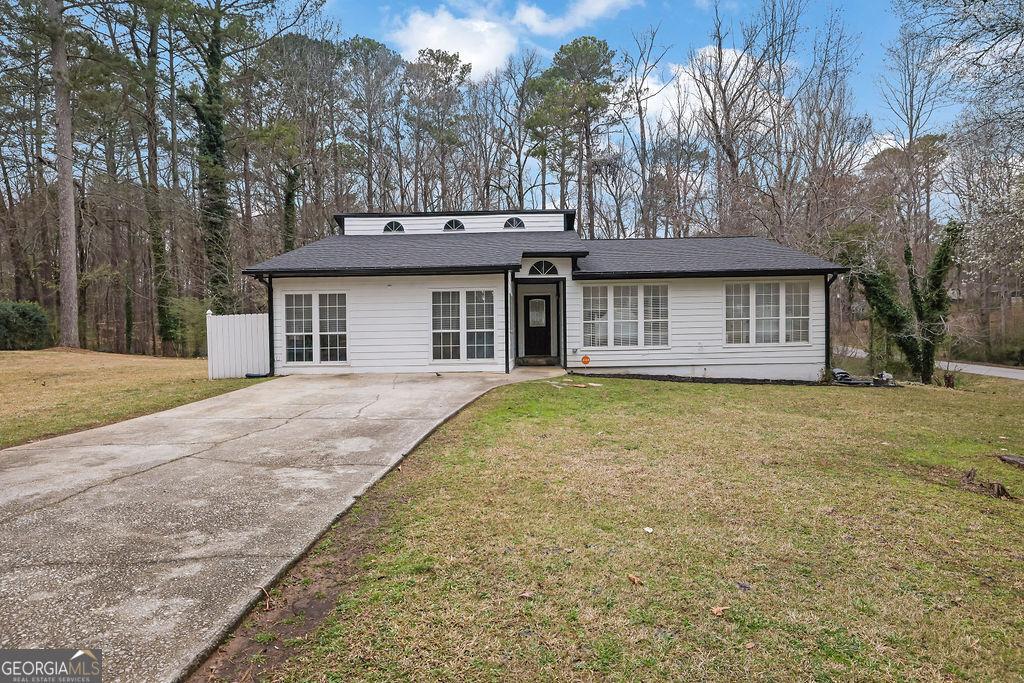 view of front facade featuring concrete driveway and a front yard