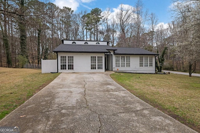 view of front facade with a shingled roof, fence, driveway, and a front lawn