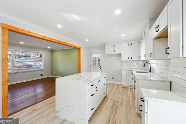 6467 Joanna St, Lithia Springs, GA 30122 - kitchen featuring a sink, a textured ceiling, backsplash, light wood-style floors, and white cabinetry