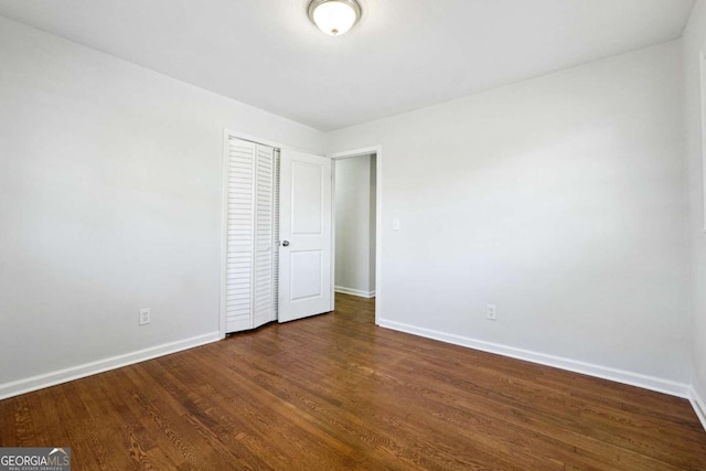 unfurnished bedroom featuring dark hardwood / wood-style flooring and a closet