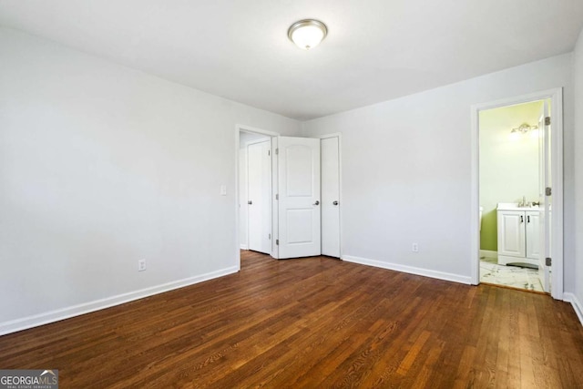 unfurnished bedroom with dark hardwood / wood-style floors and connected bathroom