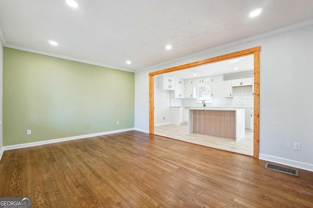 unfurnished living room with crown molding and light wood-type flooring