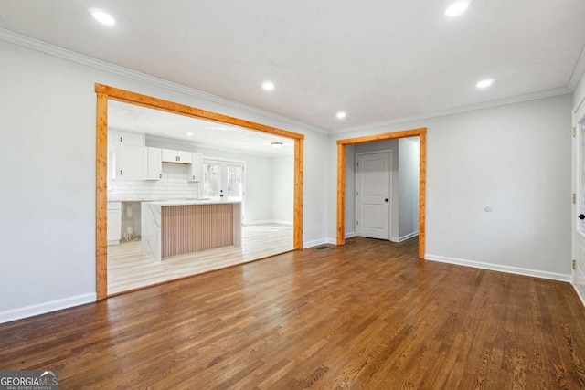 unfurnished living room featuring hardwood / wood-style flooring and ornamental molding