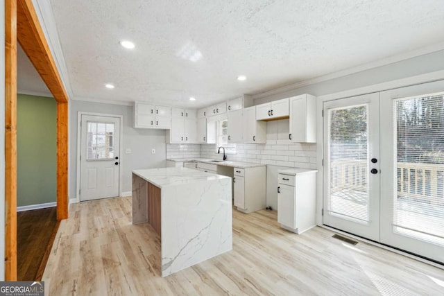 6467 Joanna St, Lithia Springs, GA 30122 - kitchen featuring a sink, a center island, ornamental molding, light stone counters, and light wood-style floors
