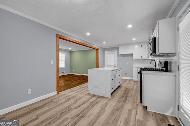 6467 Joanna St, Lithia Springs, GA 30122 - kitchen with crown molding, stainless steel microwave, recessed lighting, white cabinets, and light wood-style flooring