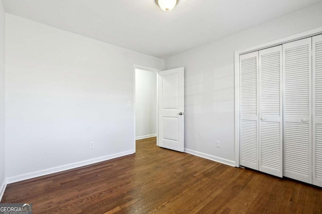 unfurnished bedroom with a closet and dark hardwood / wood-style floors