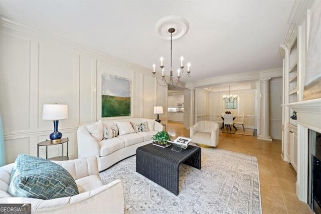 living room featuring an inviting chandelier, crown molding, and decorative columns