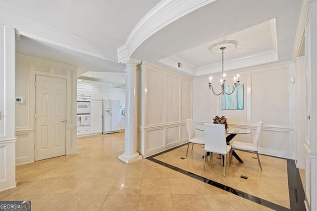 tiled dining room with ornamental molding, a tray ceiling, a chandelier, and ornate columns