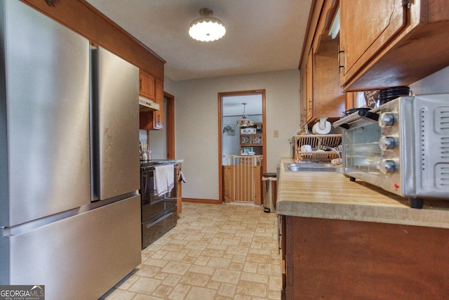 kitchen with black electric range, sink, and stainless steel fridge