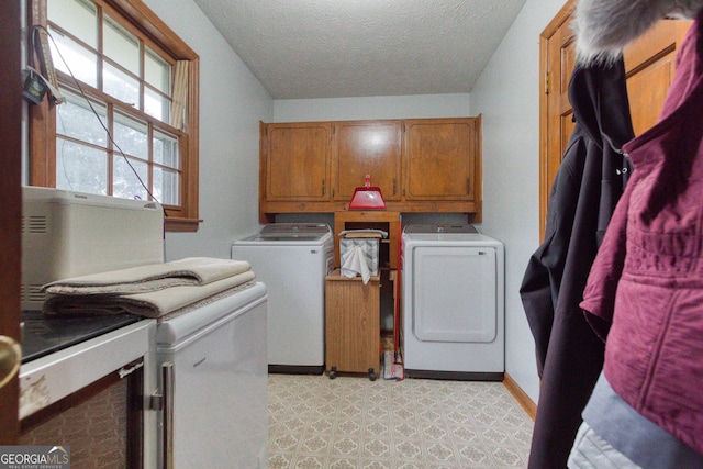 washroom with washing machine and dryer, cabinets, and a textured ceiling