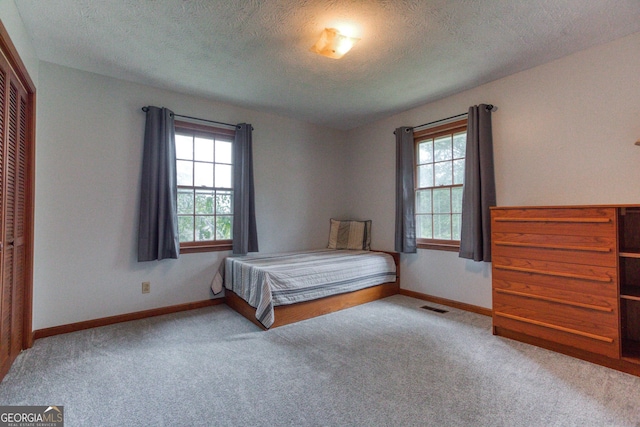 unfurnished bedroom featuring light carpet, a closet, and a textured ceiling