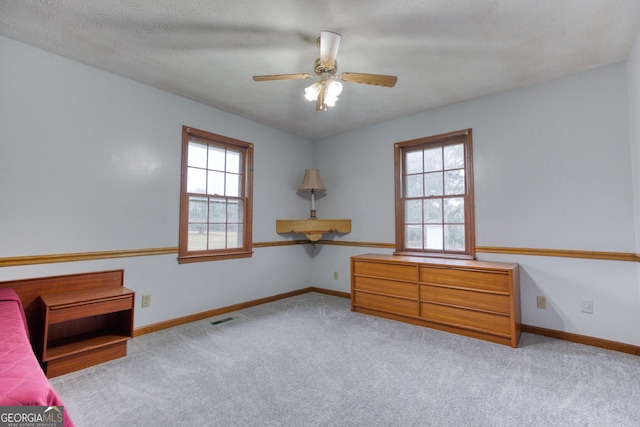 unfurnished bedroom with ceiling fan, light colored carpet, and a textured ceiling