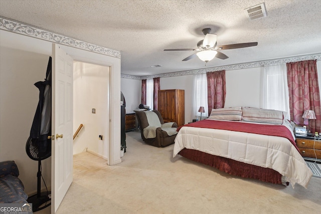 carpeted bedroom featuring ceiling fan and a textured ceiling