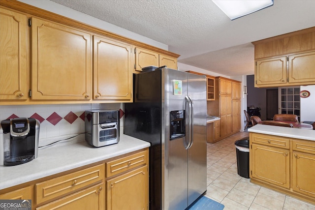 kitchen featuring light tile patterned flooring, stainless steel fridge, tasteful backsplash, and a textured ceiling