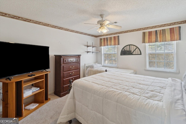 carpeted bedroom with ceiling fan and a textured ceiling