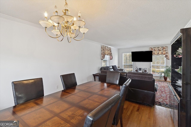 dining room with ornamental molding, dark hardwood / wood-style floors, a chandelier, and a textured ceiling