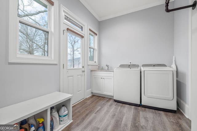 laundry area featuring sink, light hardwood / wood-style flooring, cabinets, ornamental molding, and washing machine and clothes dryer