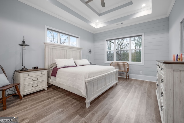 bedroom featuring a raised ceiling, ornamental molding, ceiling fan, and light hardwood / wood-style floors