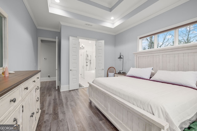 bedroom featuring a tray ceiling, dark wood-type flooring, ornamental molding, and ensuite bath