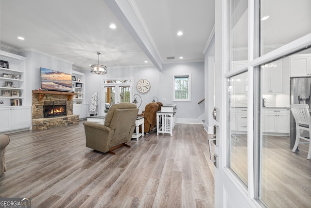 living room featuring ornamental molding, a fireplace, and light hardwood / wood-style flooring