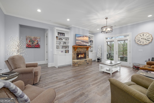 living room with built in shelves, french doors, crown molding, light hardwood / wood-style flooring, and a fireplace