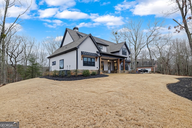 view of side of home with a yard and covered porch