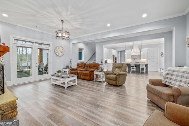 living room with crown molding, light hardwood / wood-style flooring, and a notable chandelier