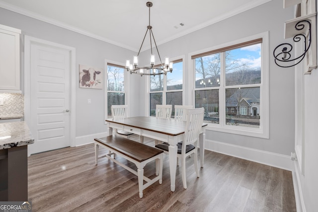 dining room with crown molding, plenty of natural light, hardwood / wood-style floors, and a notable chandelier