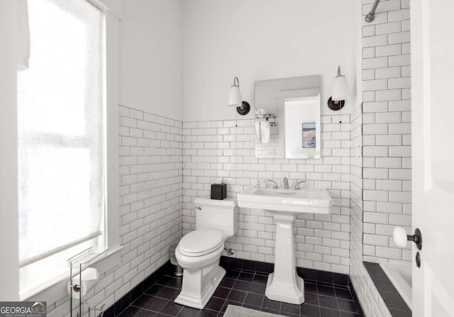 bathroom featuring tile patterned flooring, tile walls, and toilet