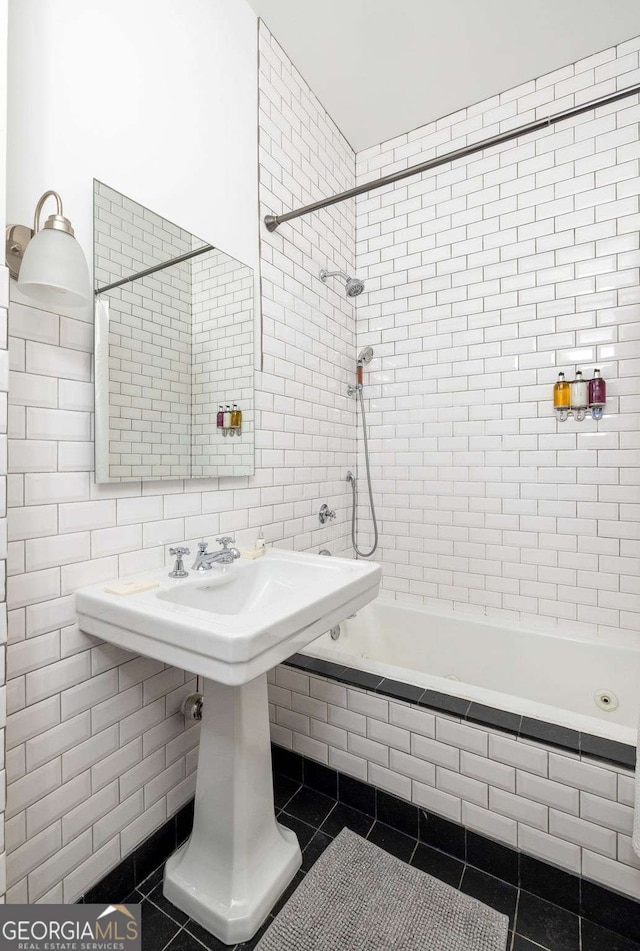 bathroom with tile patterned flooring, tiled shower / bath, tasteful backsplash, and tile walls