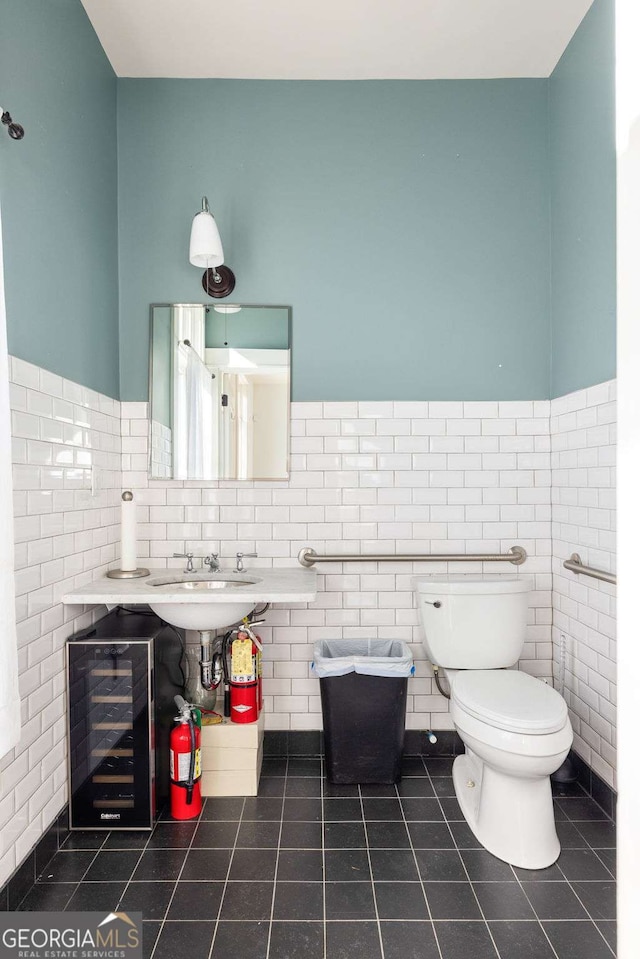 bathroom with sink, tile walls, beverage cooler, toilet, and tile patterned floors