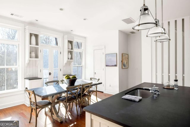 dining room featuring french doors, plenty of natural light, sink, and hardwood / wood-style floors