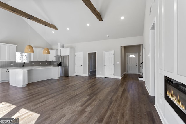 unfurnished living room with dark wood-type flooring, sink, beam ceiling, high vaulted ceiling, and a fireplace