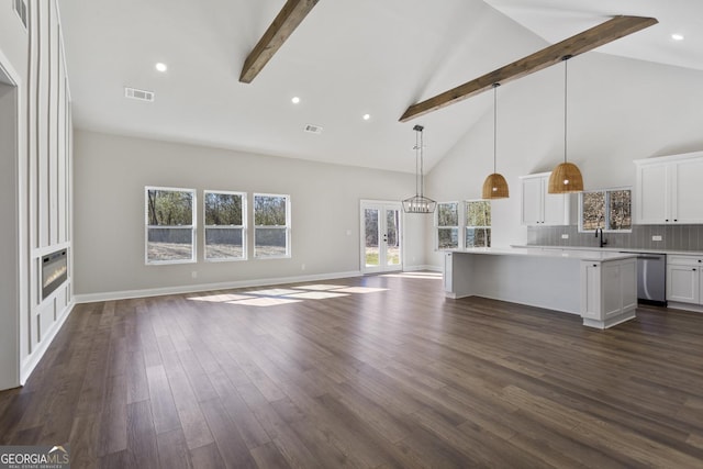 interior space with hanging light fixtures, beamed ceiling, a center island, and white cabinets